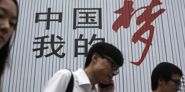 Business men walk past the local government's slogan in Chinese reading: "China My Dream" Monday, Aug. 26, 2013 in Shanghai, China's financial hub. Asian stock markets mostly rose Monday after expectations for an imminent phasing out of the Federal Reserve's monetary stimulus program began to fade. (AP Photo/Eugene Hoshiko)